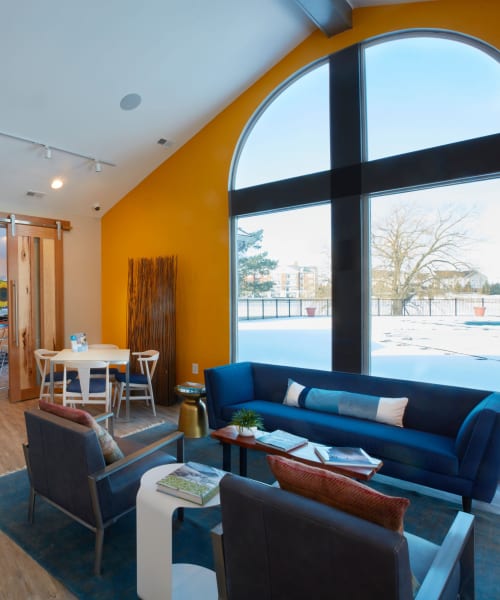 Lounge area with a sofa and armchairs by large windows in the clubhouse at Lakeside Terraces in Sterling Heights, Michigan