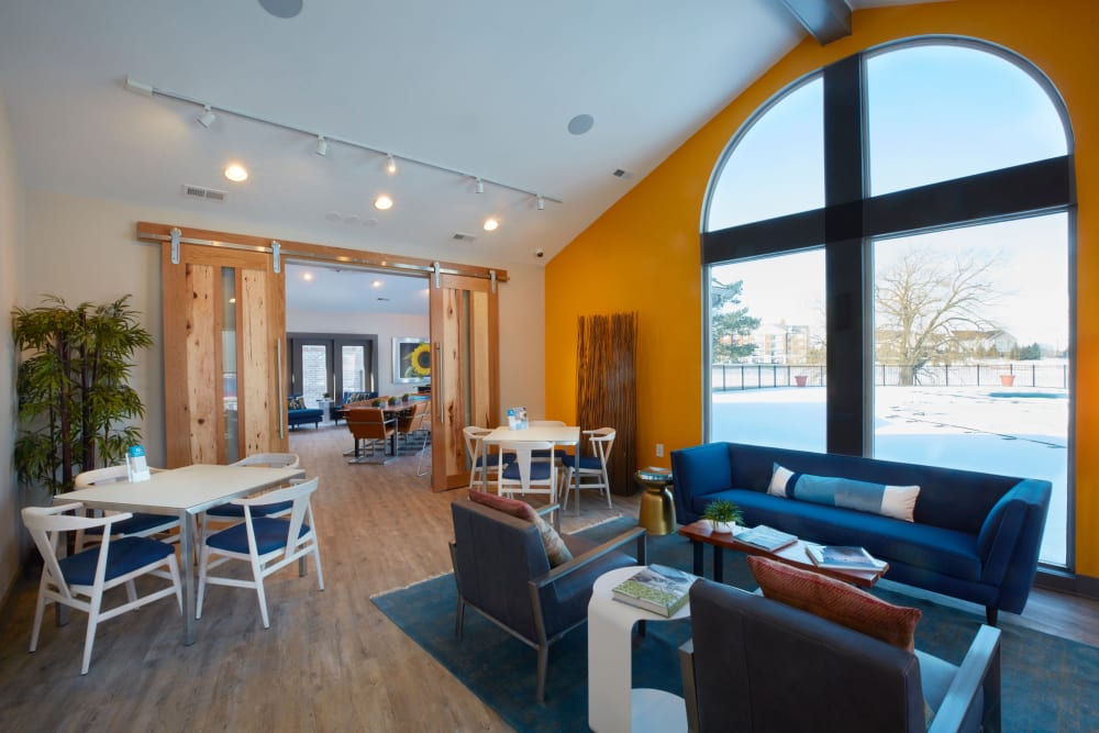 Lounge area with tables by oversized windows in the clubhouse at Lakeside Terraces in Sterling Heights, Michigan