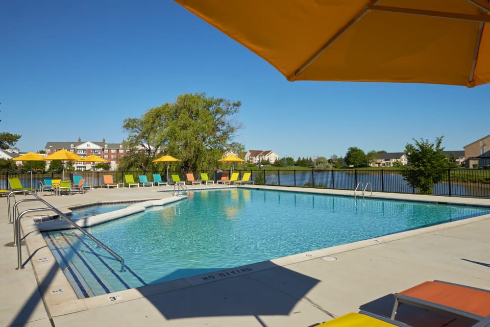Sparkling swimming pool with umbrella-shaded lounge chairs at Lakeside Terraces in Sterling Heights, Michigan