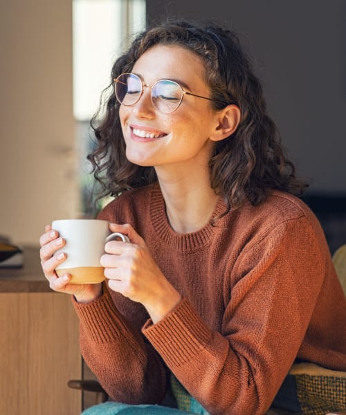 Resident relaxing with a cup of tea in her living room at Lakeside Terraces in Sterling Heights, Michigan