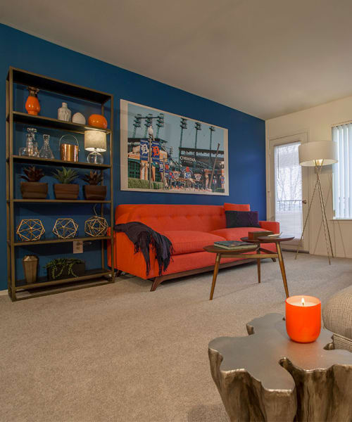 Living room with a bookshelf and red sofa at Lakeside Terraces in Sterling Heights, Michigan
